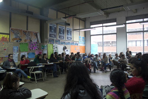 La imagen muestra a niños y adultos reunidos en un aula de la Facultad durante el último encuentro del curso-taller.