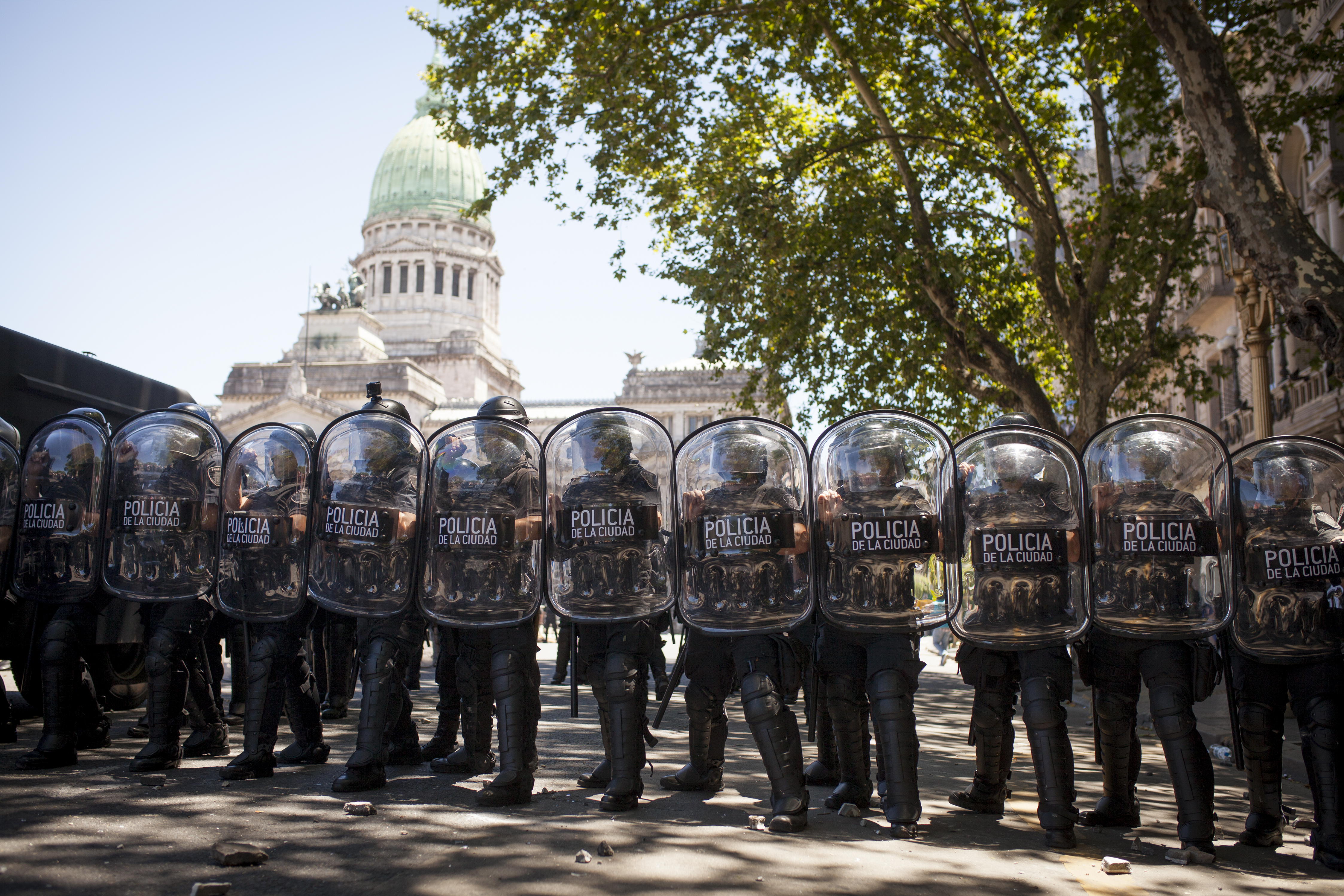 La imagen muestra un cerco policial con escudos y, en el fondo, el Congreso de la Nación.