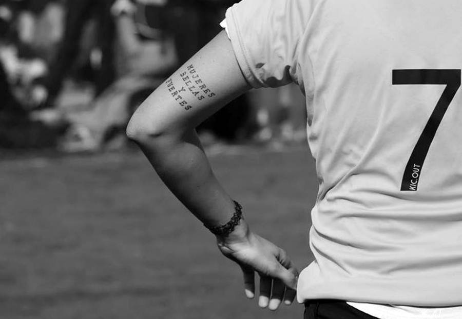 La imagen muestra a una jugadora de fútbol con la camiseta número 7 y un tatuaje en la parte anterior del brazo que dice "MUJERES BELLAS Y FUERTES".