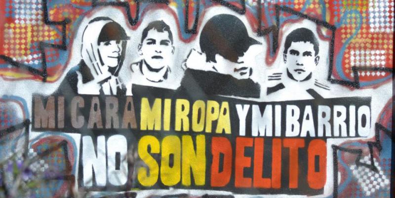 La imagen muestra un mural con un grafitti que reza "Mi cara, mi ropa y mi barrio no son delito".